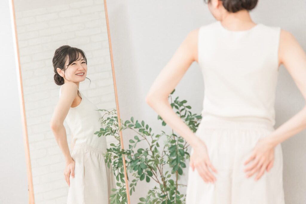 全身鏡の前でおしりを気にする笑顔女性