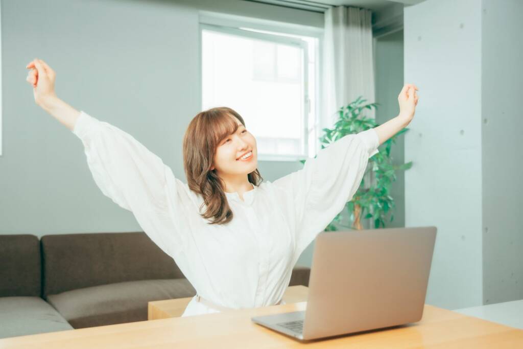 パソコンの前で背伸びする女性