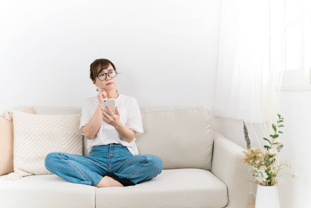 スマホを持って悩んでいる女性