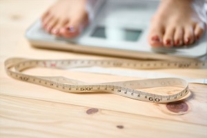 メジャーと体重計に乗る女性