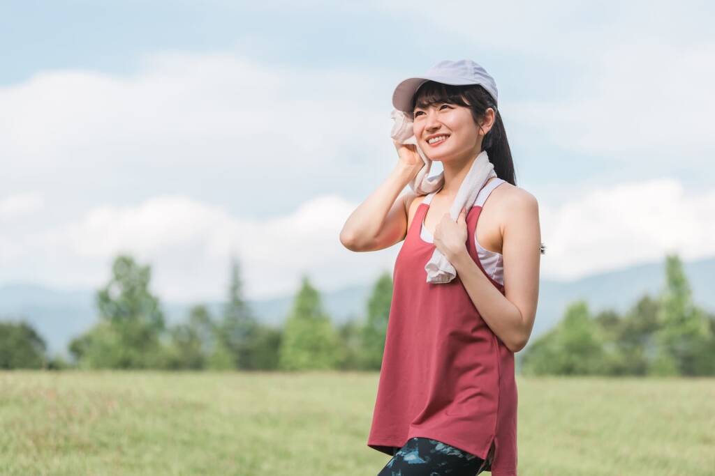 汗を拭く赤いタンクトップの女性
