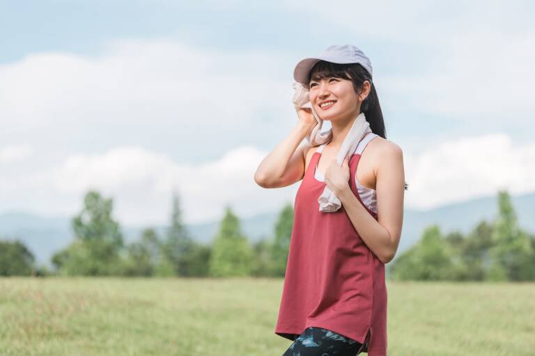 汗を拭く赤いタンクトップの女性