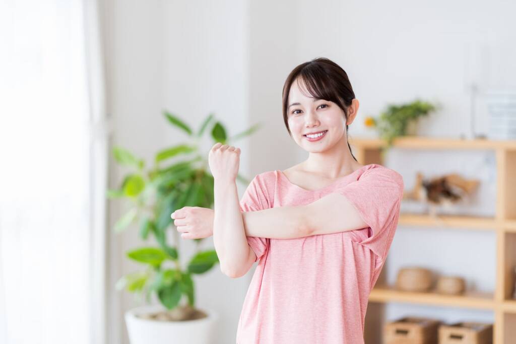 ストレッチをするピンクのTシャツの女性