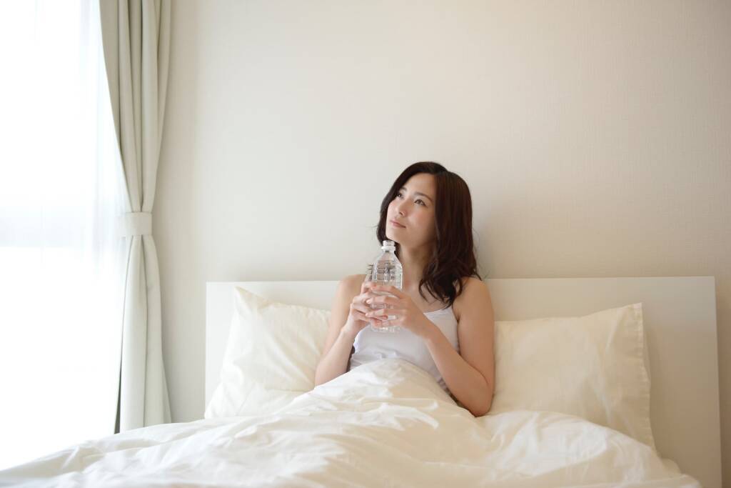 寝室でお水を飲む女性