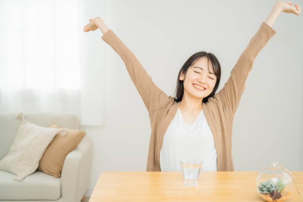 室内で背伸びする女性
