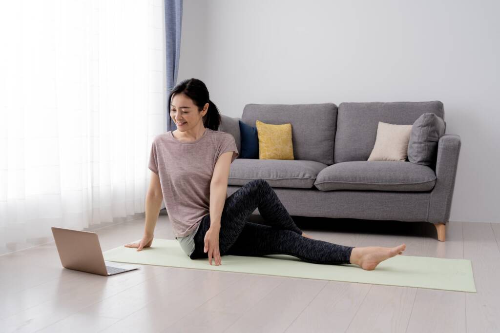 自宅で動画を見ながらストレッチする女性