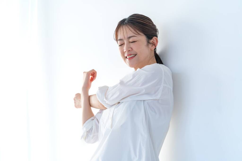 ストレッチをして腕を伸ばす中年女性