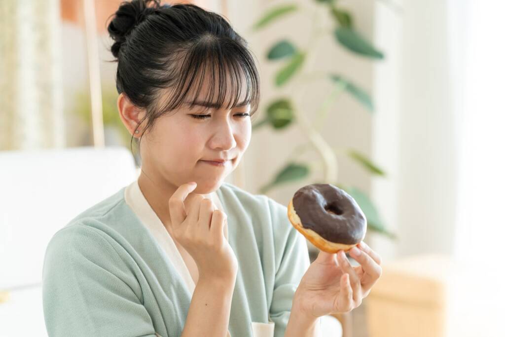 ドーナツを食べるか迷っている女性