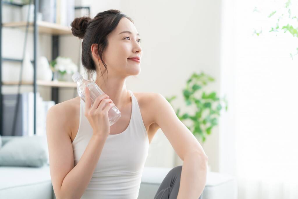 室内でペットボトルを持って汗をかく女性